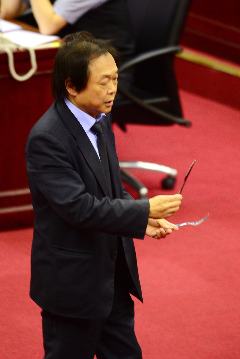 民進黨台北市議員王世堅在議場拿出刀叉,指台北市長拿刀叉吃人肉,吃人夠夠。 圖:張良一/攝 民進黨台北市議員王世堅在議場拿出刀叉,指台北市長拿刀叉吃人肉,吃人夠夠。 圖:張良一/攝