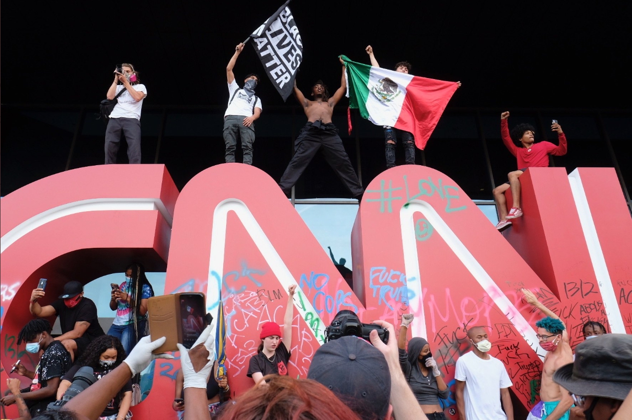 示威民眾站在「CNN」招牌上,斗大的招牌已被人噴漆、塗鴉。 圖:翻攝自推特 示威民眾站在「CNN」招牌上,斗大的招牌已被人噴漆、塗鴉。 圖:翻攝自推特