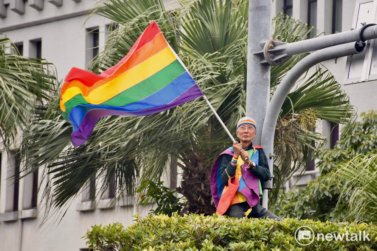 第15屆台灣同志遊行,投入婚姻平權運動多年的祁家威,總會選在遊行時,在高處搖彩虹旗,鼓舞參與的群眾。 圖:黃堃睿/提供 第15屆台灣同志遊行,投入婚姻平權運動多年的祁家威,總會選在遊行時,在高處搖彩虹旗,鼓舞參與的群眾。 圖:黃堃睿/提供