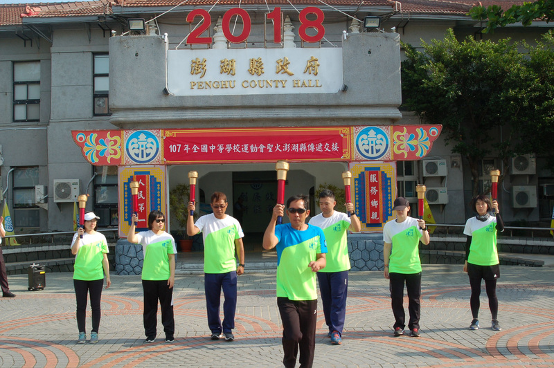 107年全國中等學校運動會聖火16日傳抵澎湖,由台中市南屯區文山國小校長邱炳彰(左)將聖火交接給縣長陳光復(右)後,隨即展開澎湖馬公市區的傳遞。 107年全國中等學校運動會聖火16日傳抵澎湖,由台中市南屯區文山國小校長邱炳彰(左)將聖火交接給縣長陳光復(右)後,隨即展開澎湖馬公市區的傳遞。