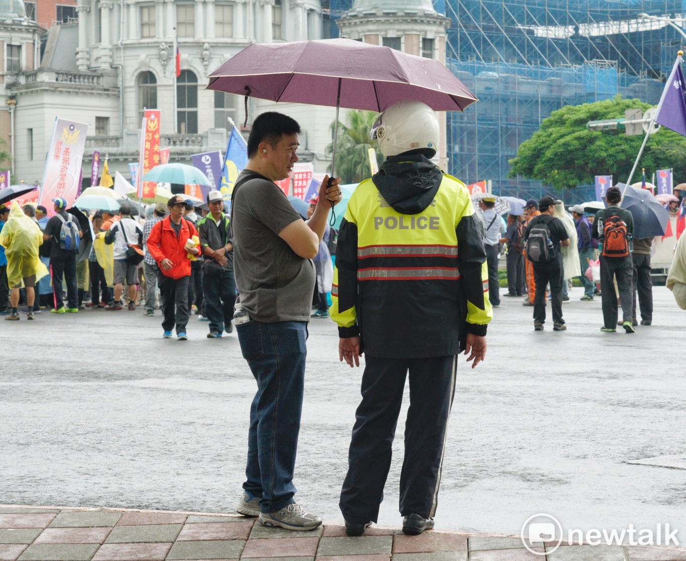 退休警察遊行到行政院前正巧下雨,一位退警幫執勤的員警撐傘。 圖 : 張良一 / 攝 退休警察遊行到行政院前正巧下雨,一位退警幫執勤的員警撐傘。 圖 : 張良一 / 攝