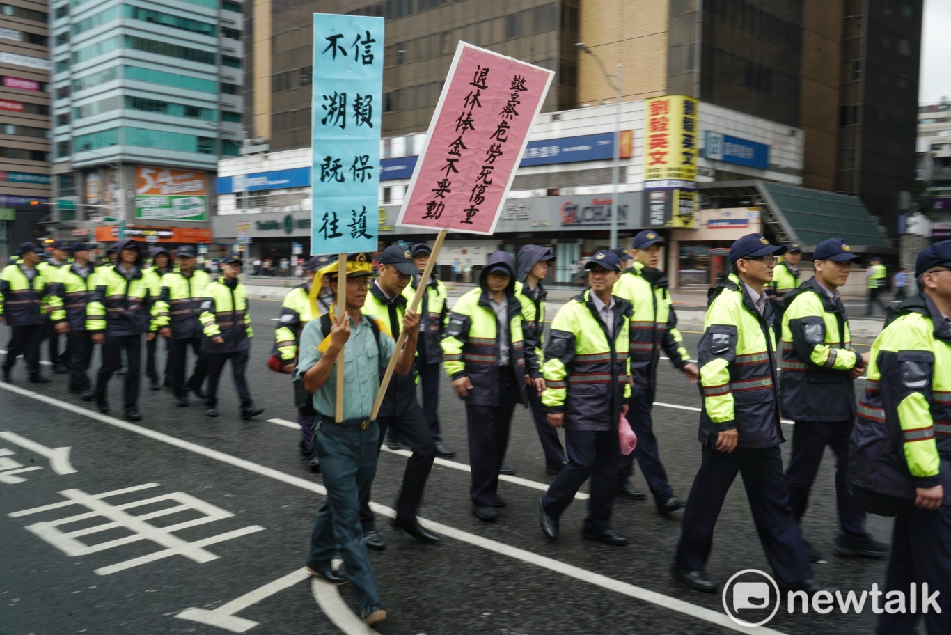 一位退警高舉「退休警察危勞死傷重,退休本俸不要動」牌子走在執勤的員警旁,這是退警遊行最關注的訴求。 圖 : 張良一 / 攝 一位退警高舉「退休警察危勞死傷重,退休本俸不要動」牌子走在執勤的員警旁,這是退警遊行最關注的訴求。 圖 : 張良一 / 攝