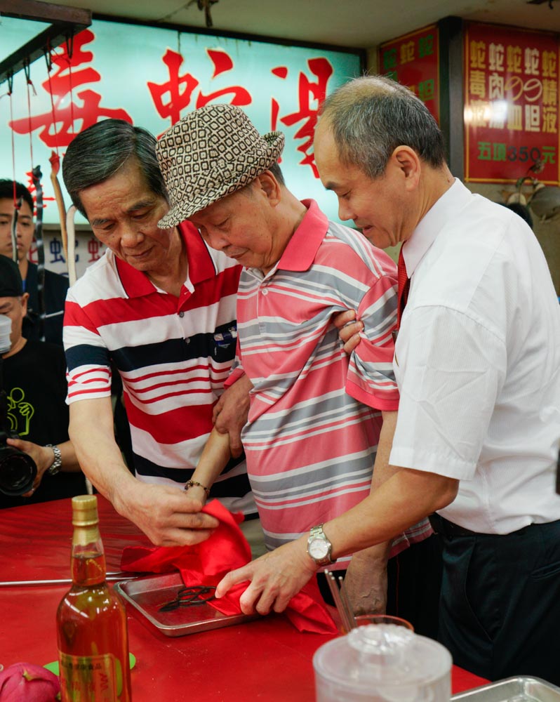亞洲蛇肉店的董事長郭來貢(中)和殺蛇師傅洪丁福(左)共同將一把使用數十載,殺蛇無數的剪刀封刀。 圖:張良一/攝 亞洲蛇肉店的董事長郭來貢(中)和殺蛇師傅洪丁福(左)共同將一把使用數十載,殺蛇無數的剪刀封刀。 圖:張良一/攝