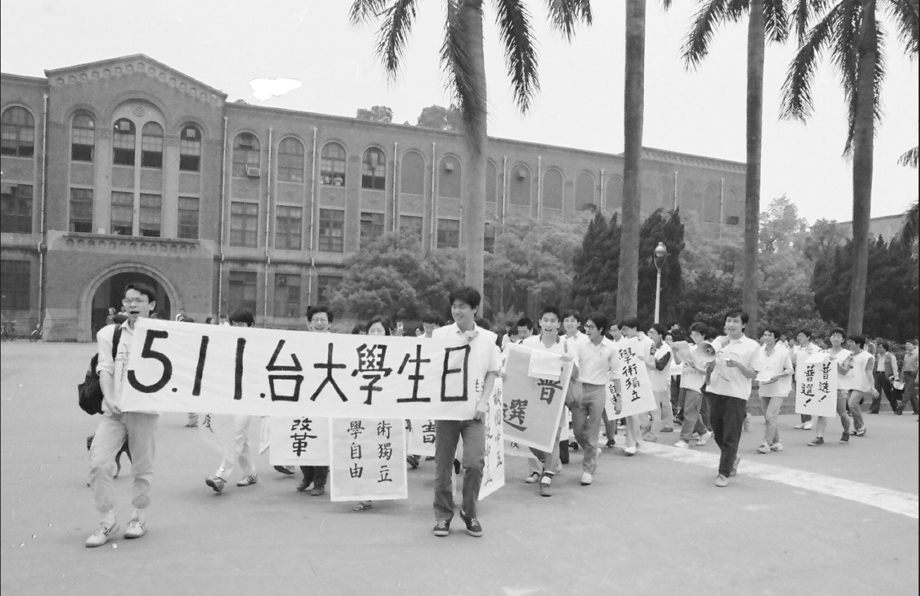 數十名學生身穿噴有紅漆「普選」字樣的衣服,從台大校門口遊行到傅鐘,再回到校門口,途中學生高喊「普選」、「我愛台大」等口號,是「511台大學生日」抗爭傳統的起源。 圖:晏山農/提供 數十名學生身穿噴有紅漆「普選」字樣的衣服,從台大校門口遊行到傅鐘,再回到校門口,途中學生高喊「普選」、「我愛台大」等口號,是「511台大學生日」抗爭傳統的起源。 圖:晏山農/提供