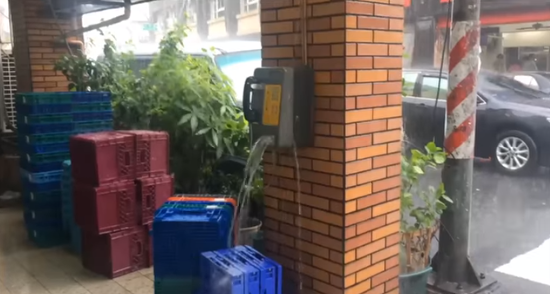 高雄一家超商外電話亭由於豪雨影響,竟化身成迷你瀑布。 圖:翻攝黑色豪門企業臉書 高雄一家超商外電話亭由於豪雨影響,竟化身成迷你瀑布。 圖:翻攝黑色豪門企業臉書