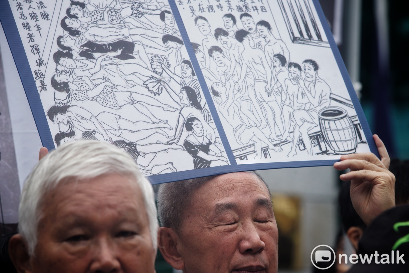 一位政治受難者代表高舉白色恐怖時代被國民黨關在大牢的非人道情況的畫像。 圖:張良一/攝 一位政治受難者代表高舉白色恐怖時代被國民黨關在大牢的非人道情況的畫像。 圖:張良一/攝