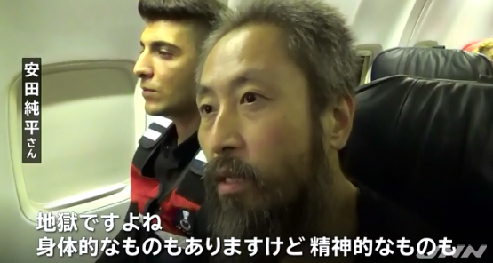 日本記者安田純平(右)遭激進蓋達組織綁架3年多獲釋,在安全人員保護下搭機回日本。 圖:翻攝TBS NEWS 日本記者安田純平(右)遭激進蓋達組織綁架3年多獲釋,在安全人員保護下搭機回日本。 圖:翻攝TBS NEWS