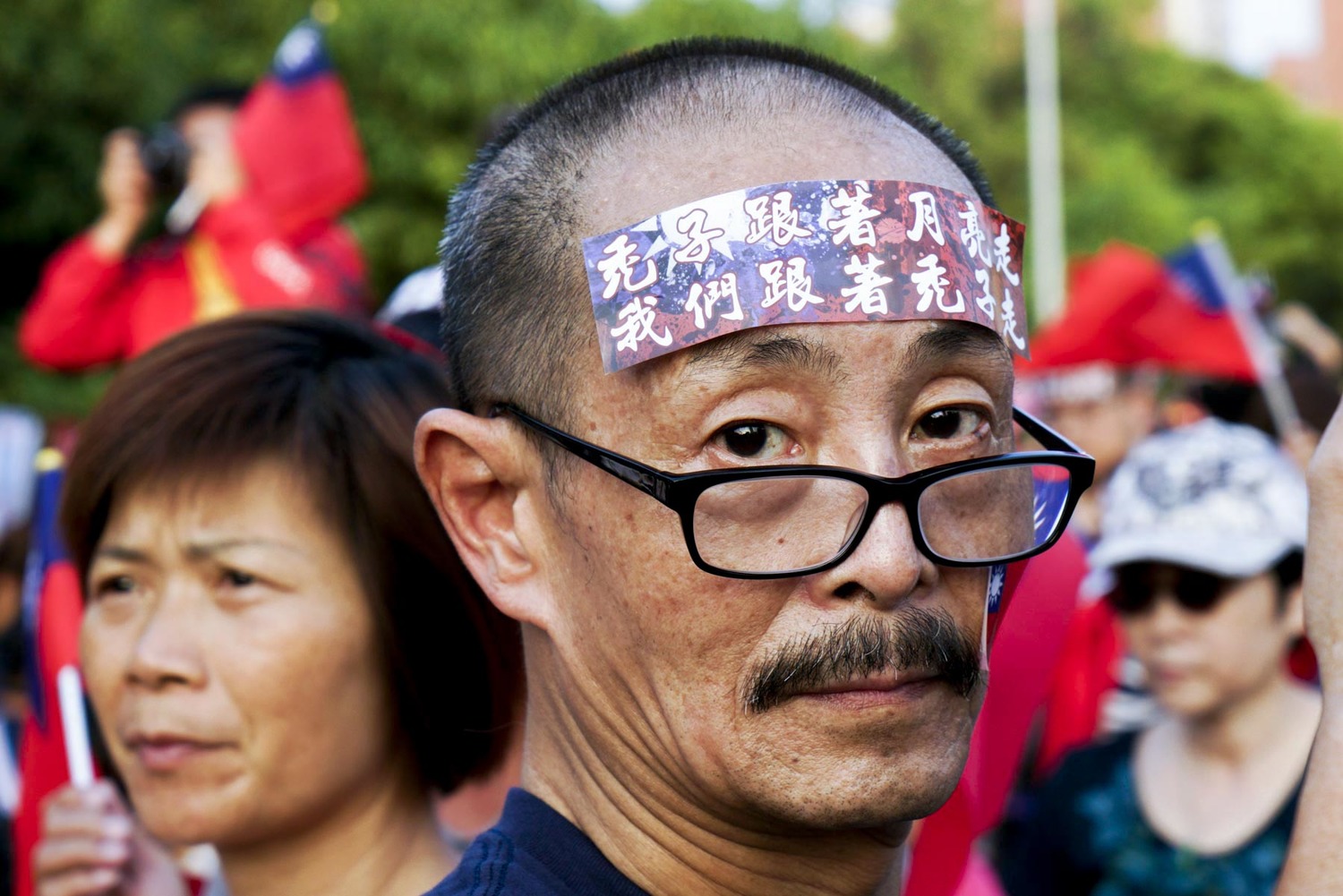 一位韓國瑜的支持者在額頭上貼上「禿子跟著月亮走 我們跟著禿子走」的貼紙。 圖:張良一/攝 一位韓國瑜的支持者在額頭上貼上「禿子跟著月亮走 我們跟著禿子走」的貼紙。 圖:張良一/攝