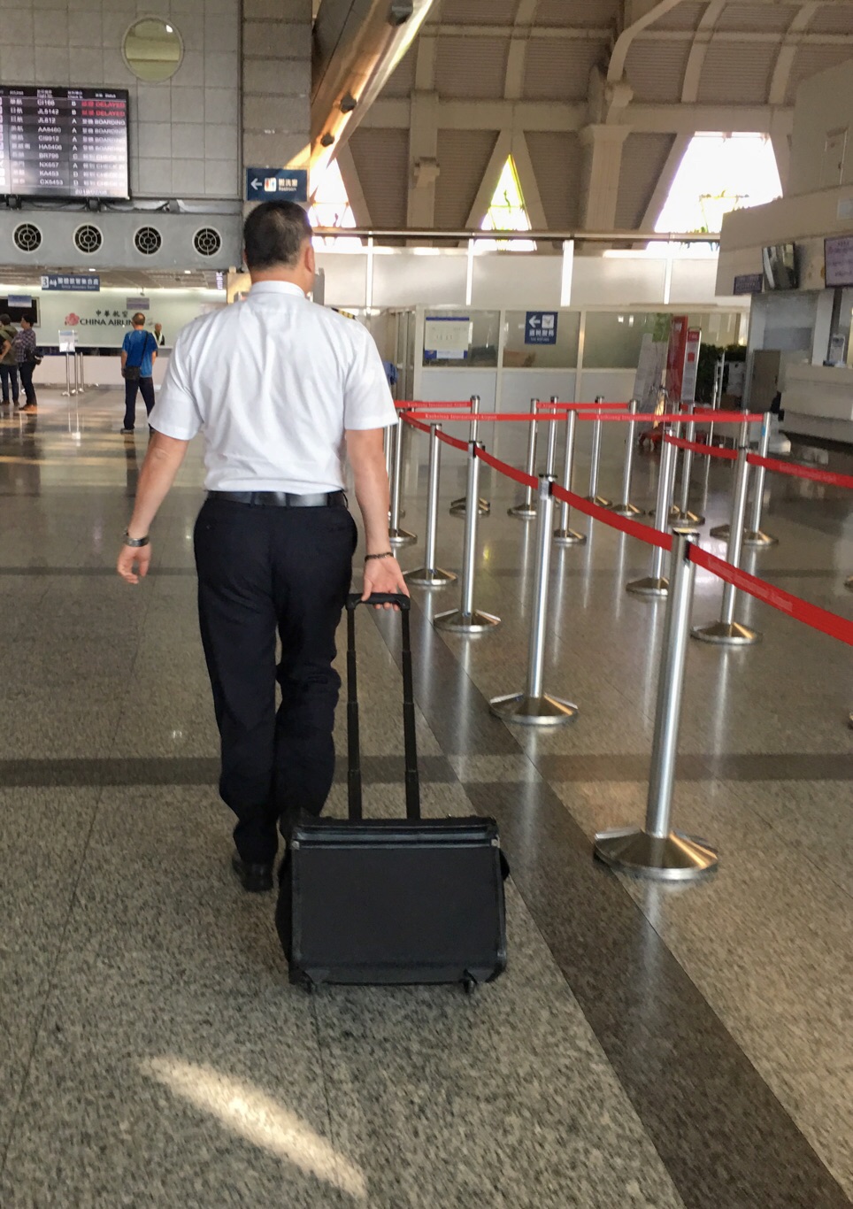 一位沒有參與罷工的華航機師拉著行李箱走進高雄小港國際機場出境大廳時,經過空蕩蕩的華航報到櫃檯,準備執勤。 圖:張良一攝 一位沒有參與罷工的華航機師拉著行李箱走進高雄小港國際機場出境大廳時,經過空蕩蕩的華航報到櫃檯,準備執勤。 圖:張良一攝