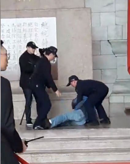 台灣國辦公室主任陳峻涵拿著魷魚糜朝蔣中正銅像丟擲,遭警方壓制在地。 圖:翻攝自台灣國辦公室臉書 台灣國辦公室主任陳峻涵拿著魷魚糜朝蔣中正銅像丟擲,遭警方壓制在地。 圖:翻攝自台灣國辦公室臉書