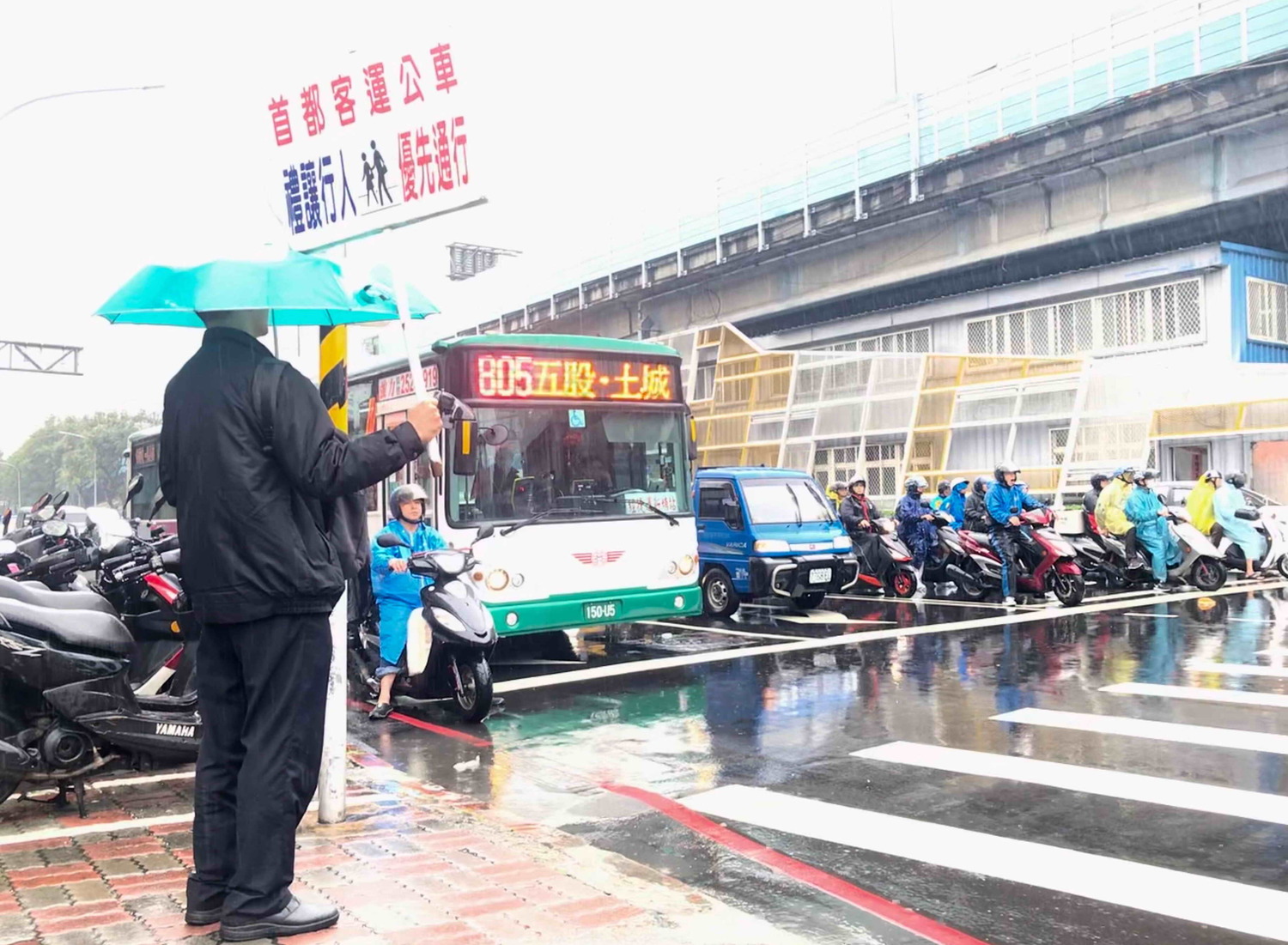 首都客運派員在路口的停等區,舉牌向公車駕駛宣導「禮讓行人」。 圖:新北市交通局提供 首都客運派員在路口的停等區,舉牌向公車駕駛宣導「禮讓行人」。 圖:新北市交通局提供