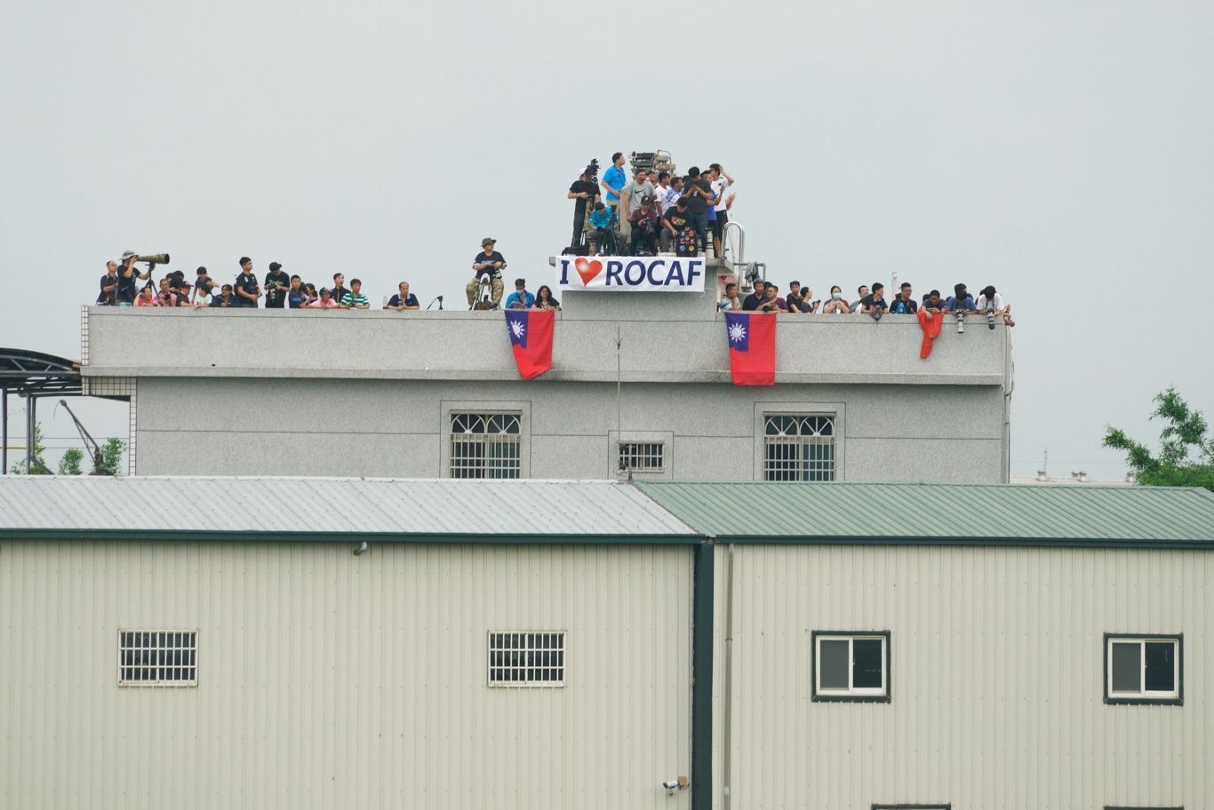 一些民眾在屋頂上掛出中華民國國旗和我愛中華民國空軍的英文布條,向參與戰機起降演練的官兵加油打氣。 圖:張良一/攝 一些民眾在屋頂上掛出中華民國國旗和我愛中華民國空軍的英文布條,向參與戰機起降演練的官兵加油打氣。 圖:張良一/攝