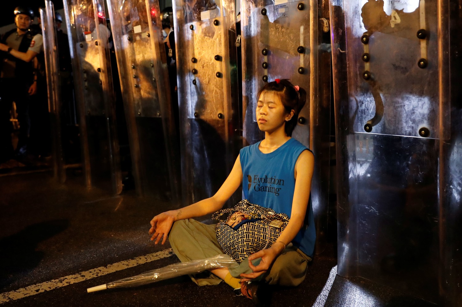 有位民眾在手持盾牌的港警前靜坐,形成強烈對比。圖:達志影像/路透社 有位民眾在手持盾牌的港警前靜坐,形成強烈對比。圖:達志影像/路透社