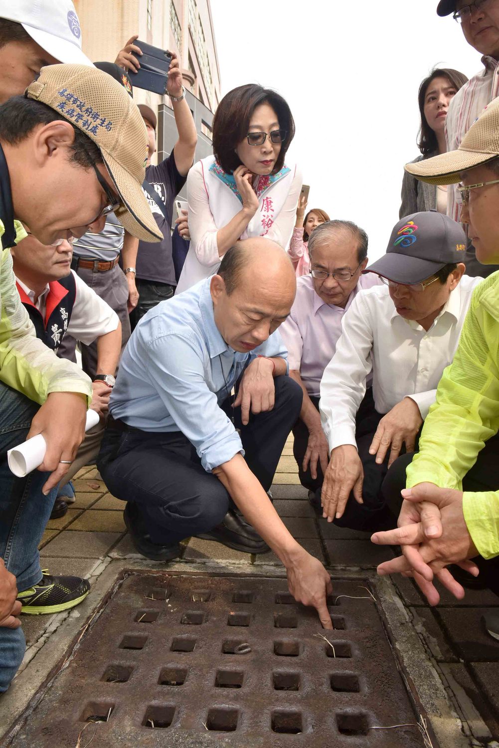 韓國瑜蹲下查看水溝,康裕成在後緊盯。 圖:高雄市政府/提供 韓國瑜蹲下查看水溝,康裕成在後緊盯。 圖:高雄市政府/提供