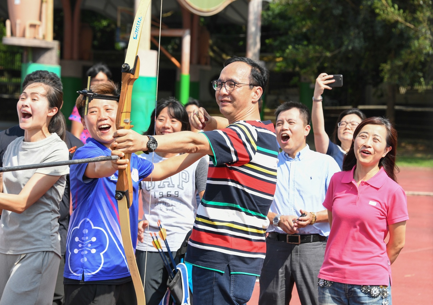 明德高中校友、奧運名將「雷母」雷千瑩(右2藍衣者)教朱立倫拉弓射箭。 圖:朱立倫辦公室/提供 明德高中校友、奧運名將「雷母」雷千瑩(右2藍衣者)教朱立倫拉弓射箭。 圖:朱立倫辦公室/提供