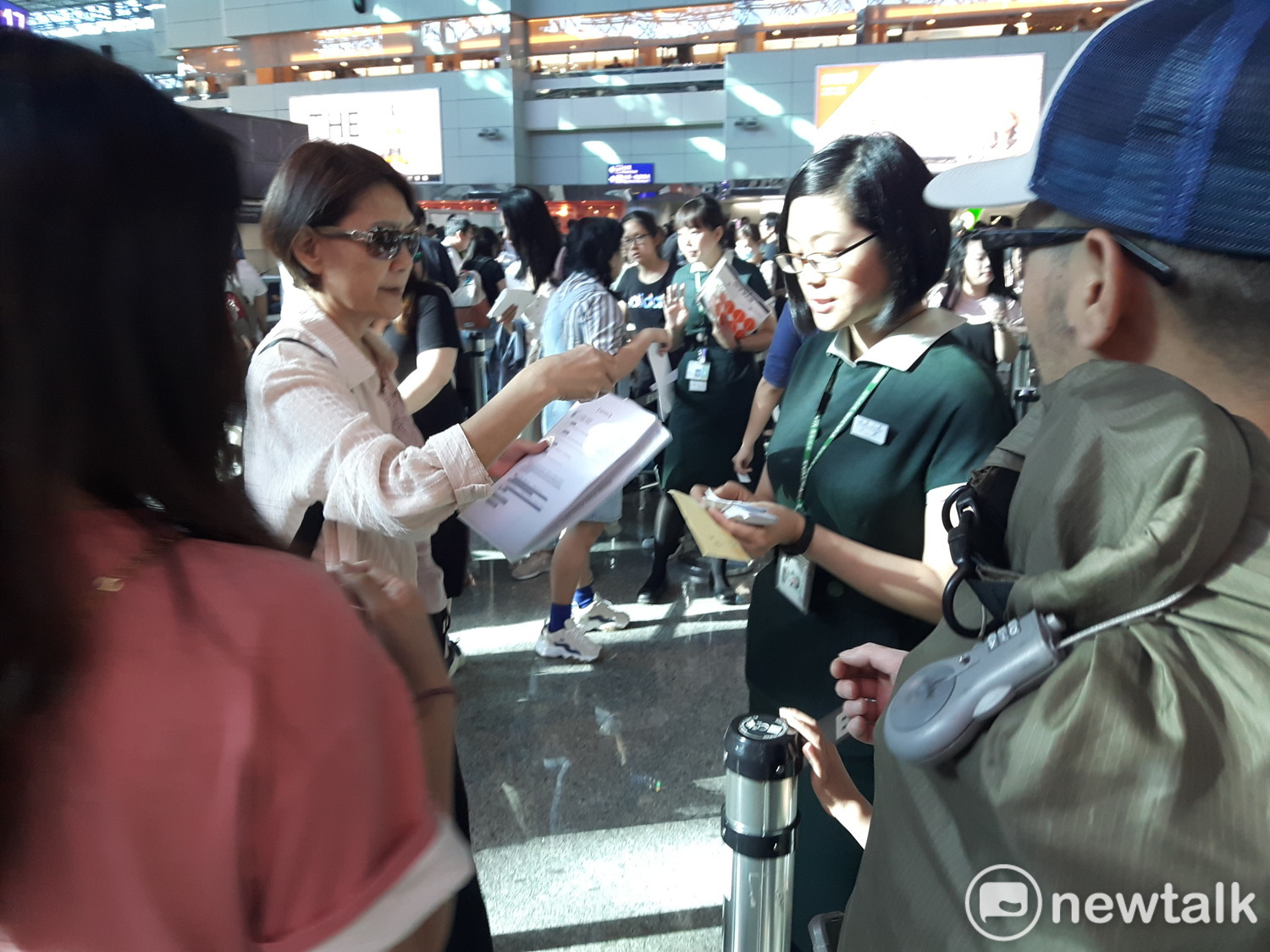 長榮地勤人員正發排隊號碼牌給旅客等候換退票。 圖:林昀真/攝 長榮地勤人員正發排隊號碼牌給旅客等候換退票。 圖:林昀真/攝