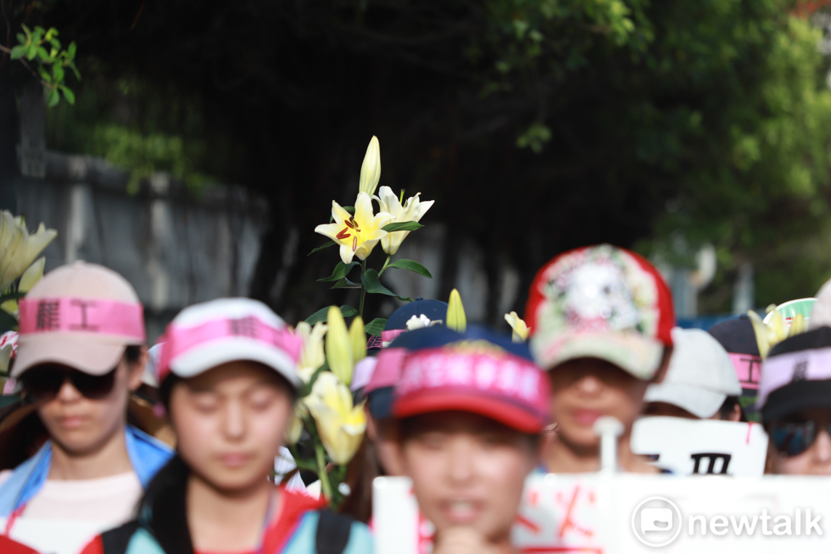 現場許多會員手捧百合花,站在工會代表後方。 圖:謝佳真/攝 現場許多會員手捧百合花,站在工會代表後方。 圖:謝佳真/攝