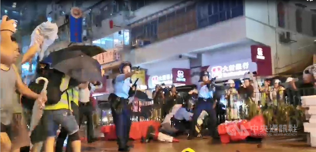 香港「反送中」遊行今晚疑似首度出現警方發射實彈。入夜後,有約10名員警在抗爭現場遭示威者包圍追打,被圍員警拔出隨身的左輪手槍對空鳴槍示警,示威者一哄而散,並遭增援的員警追捕。 圖:中央社提供 香港「反送中」遊行今晚疑似首度出現警方發射實彈。入夜後,有約10名員警在抗爭現場遭示威者包圍追打,被圍員警拔出隨身的左輪手槍對空鳴槍示警,示威者一哄而散,並遭增援的員警追捕。 圖:中央社提供