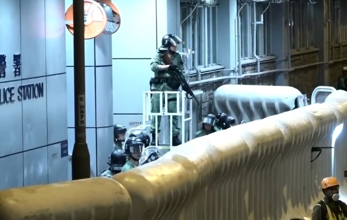 示威者再度圍堵旺角警署,警方持槍嚴陣以待。 圖:翻攝香港電台視像新聞畫面 示威者再度圍堵旺角警署,警方持槍嚴陣以待。 圖:翻攝香港電台視像新聞畫面
