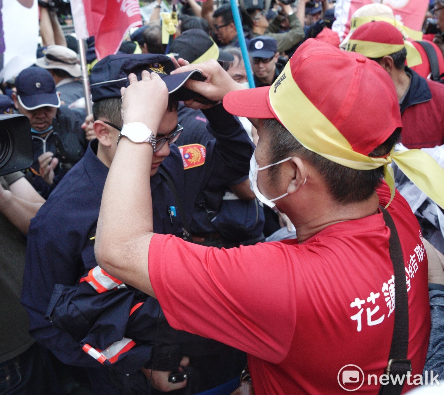 一位退警在衝突中幫一位現役警察戴好帽子。 圖:張良一/攝 一位退警在衝突中幫一位現役警察戴好帽子。 圖:張良一/攝