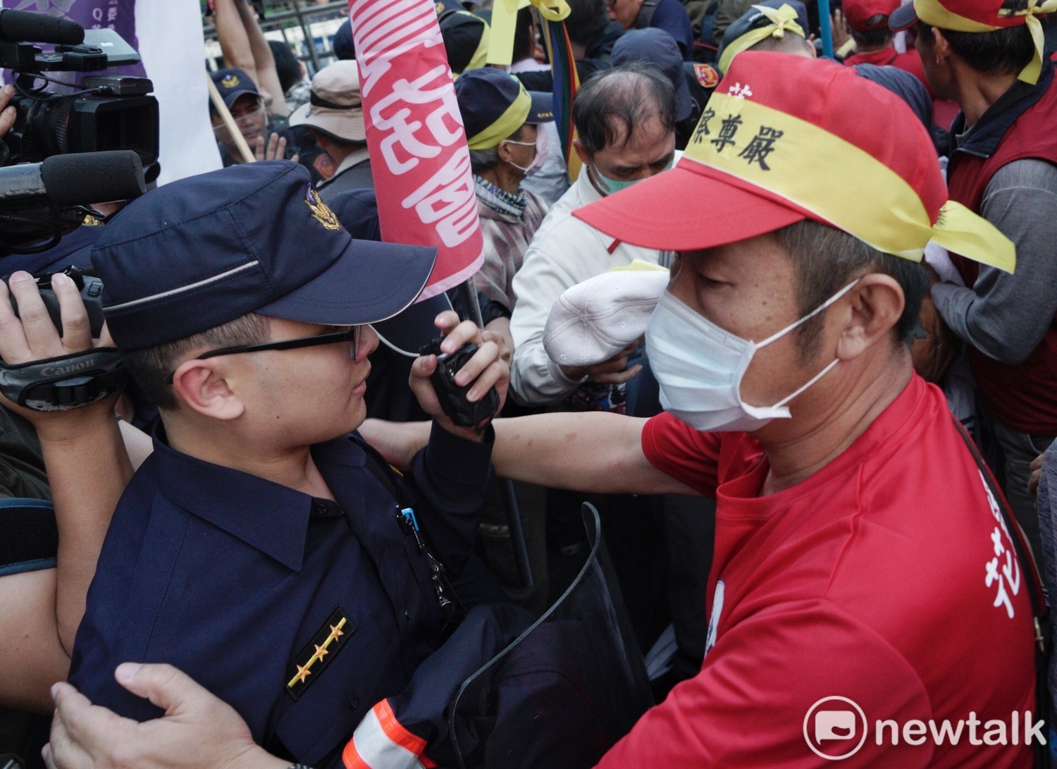 一位退警在衝突中幫一位現役警察戴好帽子,並拍肩為現役警員打氣。 圖:張良一/攝 一位退警在衝突中幫一位現役警察戴好帽子,並拍肩為現役警員打氣。 圖:張良一/攝