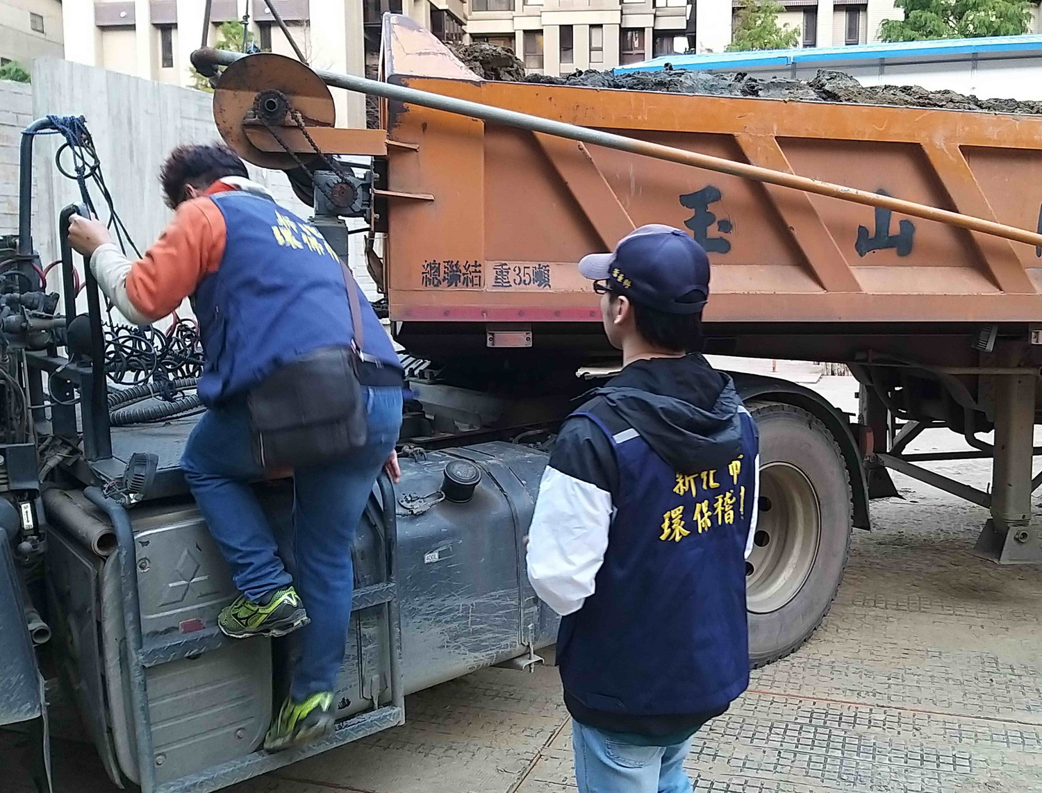 新北市環保稽查員爬上土方車查看車斗內土石方狀況。 圖:新北市環保局提供 新北市環保稽查員爬上土方車查看車斗內土石方狀況。 圖:新北市環保局提供