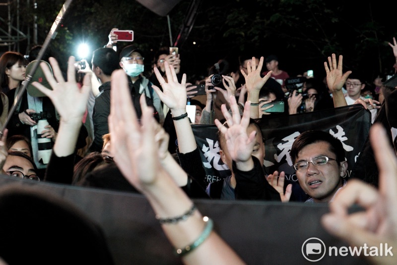 港人在「光復香港時代革命」旗幟後,以不曝光方式比出五大訴求手勢。 圖:張良一/攝 港人在「光復香港時代革命」旗幟後,以不曝光方式比出五大訴求手勢。 圖:張良一/攝