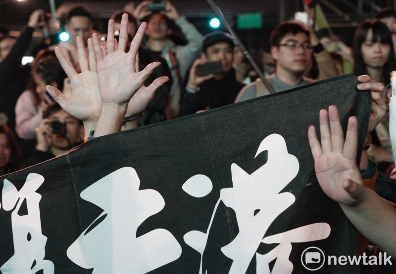 港人在「光復香港時代革命」旗幟後,以不曝光方式比出五大訴求手勢。 圖:張良一/攝 港人在「光復香港時代革命」旗幟後,以不曝光方式比出五大訴求手勢。 圖:張良一/攝