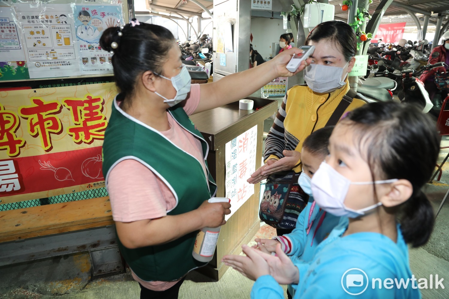 市場人員為攤商和顧客測量額溫,落實防疫工作。 圖:黃博郎/攝 市場人員為攤商和顧客測量額溫,落實防疫工作。 圖:黃博郎/攝