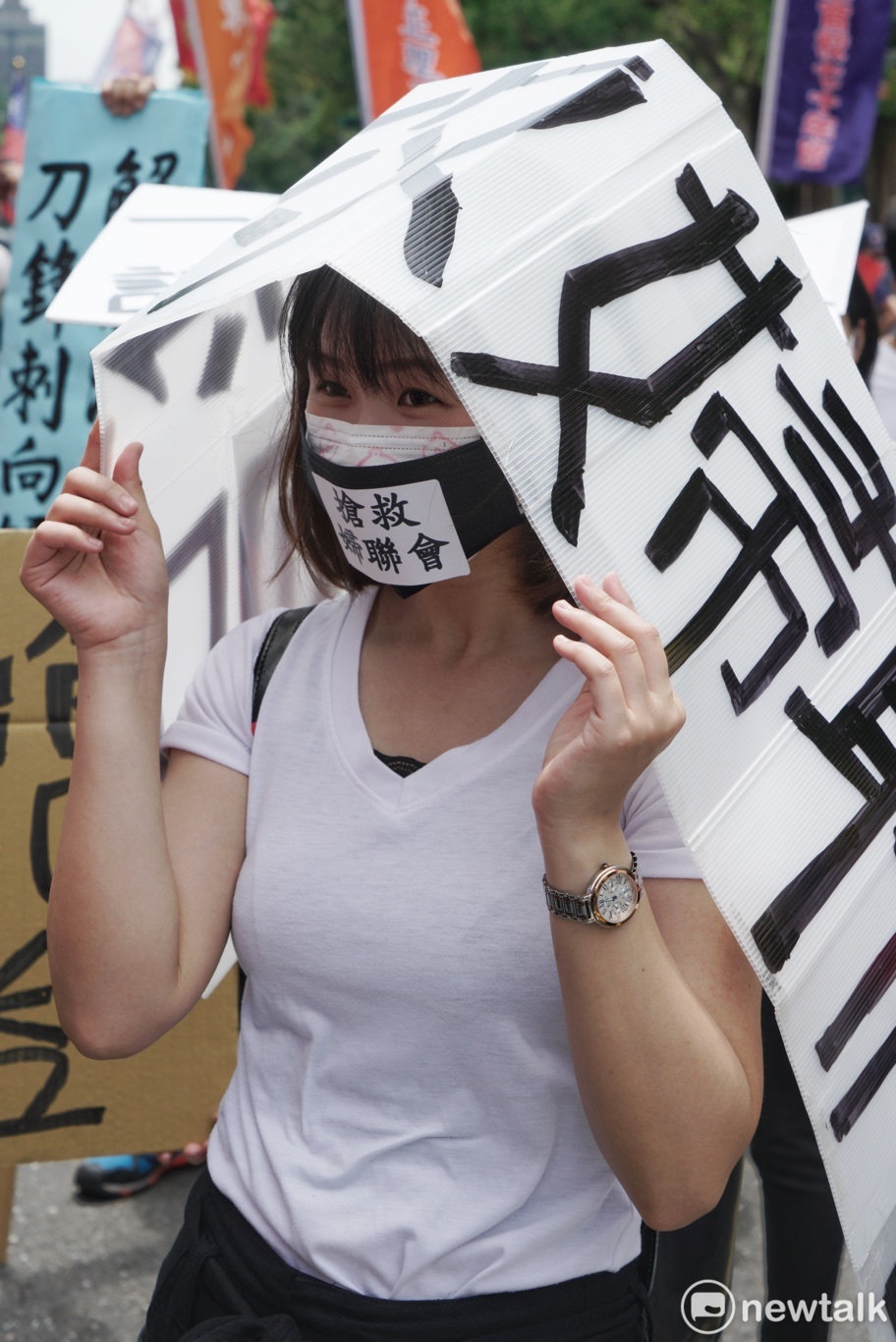 一位民眾戴口罩和寫著婦聯會的白色牌子聲援婦聯會。 圖:張良一/攝 一位民眾戴口罩和寫著婦聯會的白色牌子聲援婦聯會。 圖:張良一/攝
