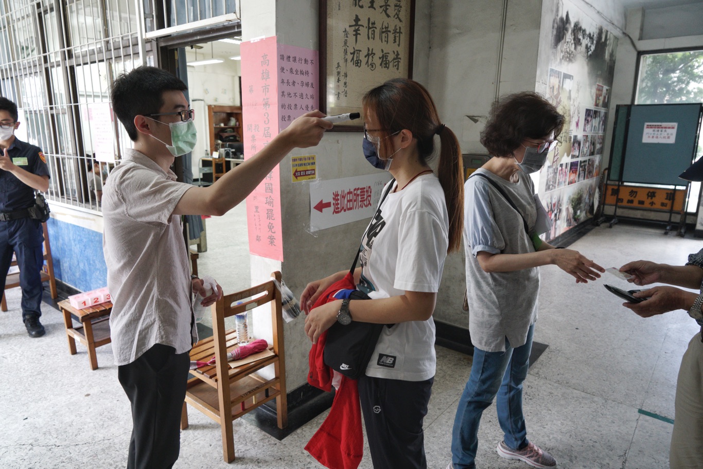 8點投票前,選務人員幫選民量體溫。。 圖:張良一/攝 8點投票前,選務人員幫選民量體溫。。 圖:張良一/攝