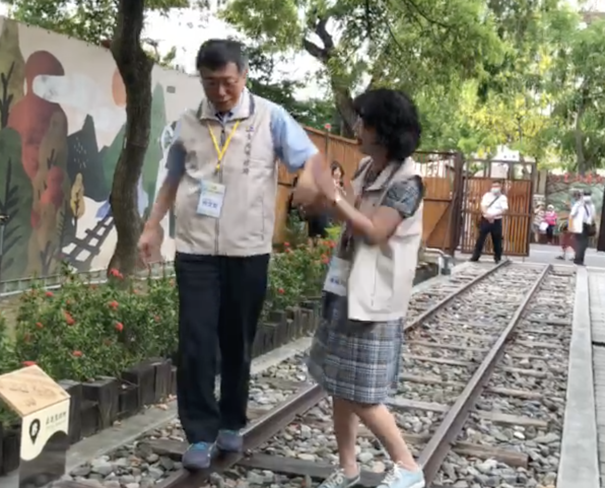 台北市長柯文哲牽妻子陳佩琪手走鐵軌,柯重心不穩多次跌下,讓陳佩琪忍不住伸手打了柯的手。 圖:翻攝影片 台北市長柯文哲牽妻子陳佩琪手走鐵軌,柯重心不穩多次跌下,讓陳佩琪忍不住伸手打了柯的手。 圖:翻攝影片