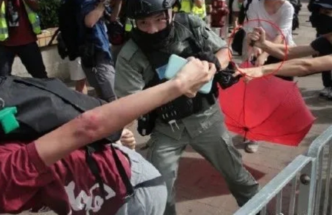 香港七一遊行刺警案中,持紅傘的白衣女子被警方懷疑是女哨兵。 圖:翻攝自北京日報 香港七一遊行刺警案中,持紅傘的白衣女子被警方懷疑是女哨兵。 圖:翻攝自北京日報