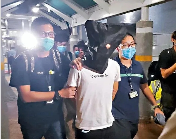香港七一遊行刺警案的涉嫌男子,被警方帶下飛機。 圖:翻攝自北京日報 香港七一遊行刺警案的涉嫌男子,被警方帶下飛機。 圖:翻攝自北京日報