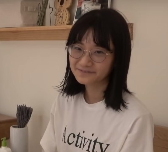 愛莉莎莎戴著圓框眼鏡與及肩的半長髮,非常像學生。 圖:翻攝YouTube 愛莉莎莎戴著圓框眼鏡與及肩的半長髮,非常像學生。 圖:翻攝YouTube