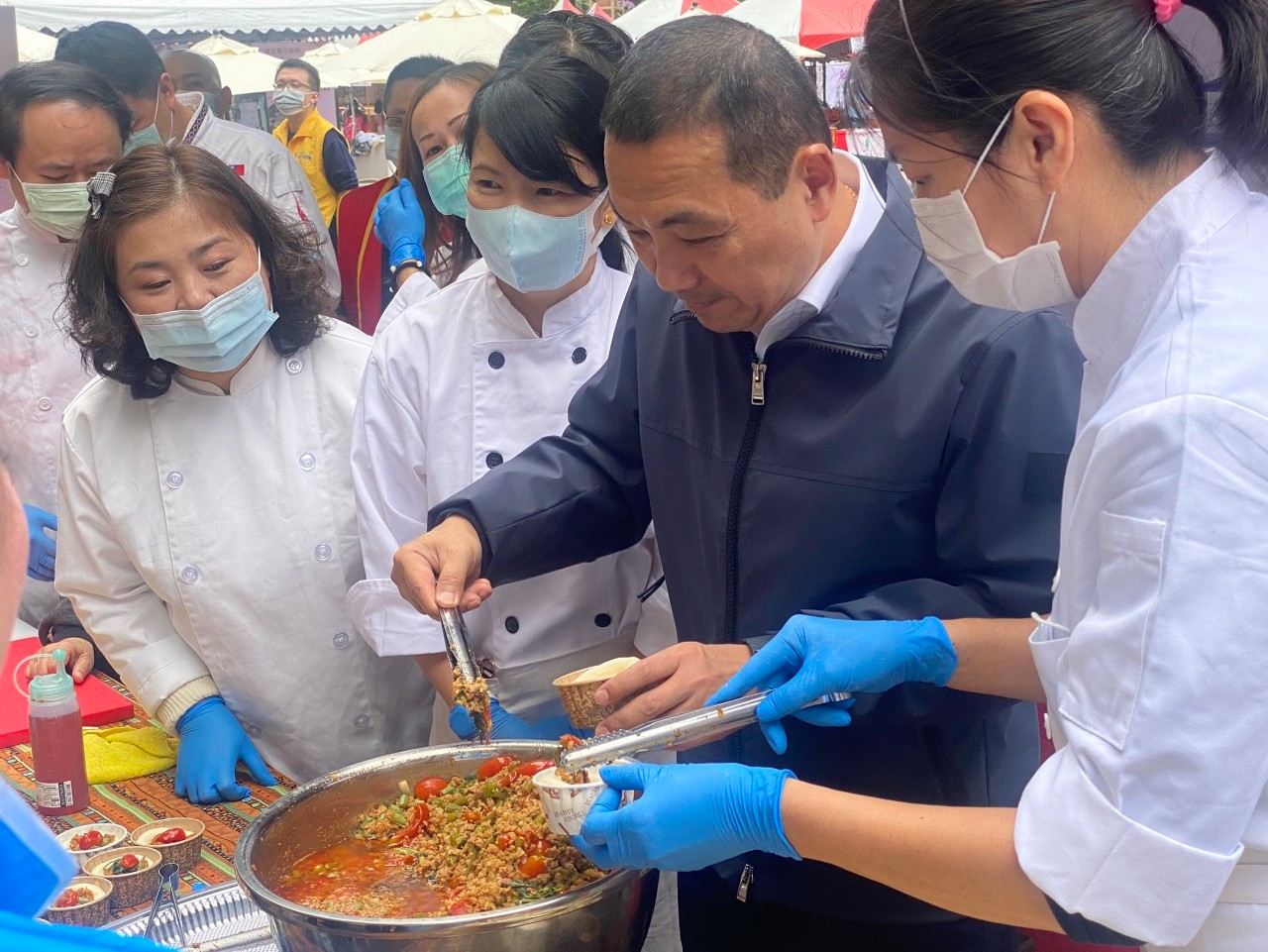 侯友宜巡視成果展攤位,品嚐打拋豬口味的窩窩頭。 圖:新北市勞工局提供 侯友宜巡視成果展攤位,品嚐打拋豬口味的窩窩頭。 圖:新北市勞工局提供
