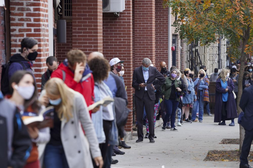 在紐約，提前投票已經持續了好幾天。紐約市長比爾‧白思豪（中，插腰看手機者）27日和民眾一起排了三個多小時隊才完成投票，他呼籲選舉委員會增加人員和投票設備，以減少選民的等待時間。 圖 : 翻攝自新華社。