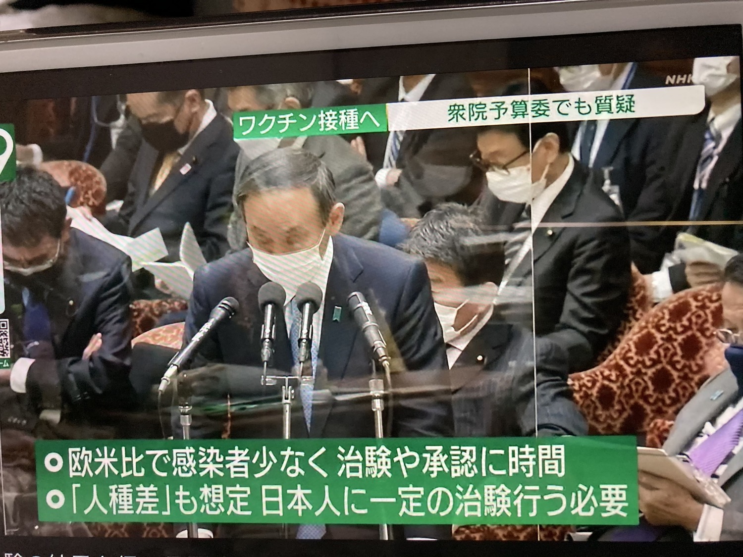 菅義偉在國會辯解日本打疫苗落後是因為確診者比歐美少一個零以及願意接受臨床實驗的日本人很少。 圖:翻攝自NHK 菅義偉在國會辯解日本打疫苗落後是因為確診者比歐美少一個零以及願意接受臨床實驗的日本人很少。 圖:翻攝自NHK