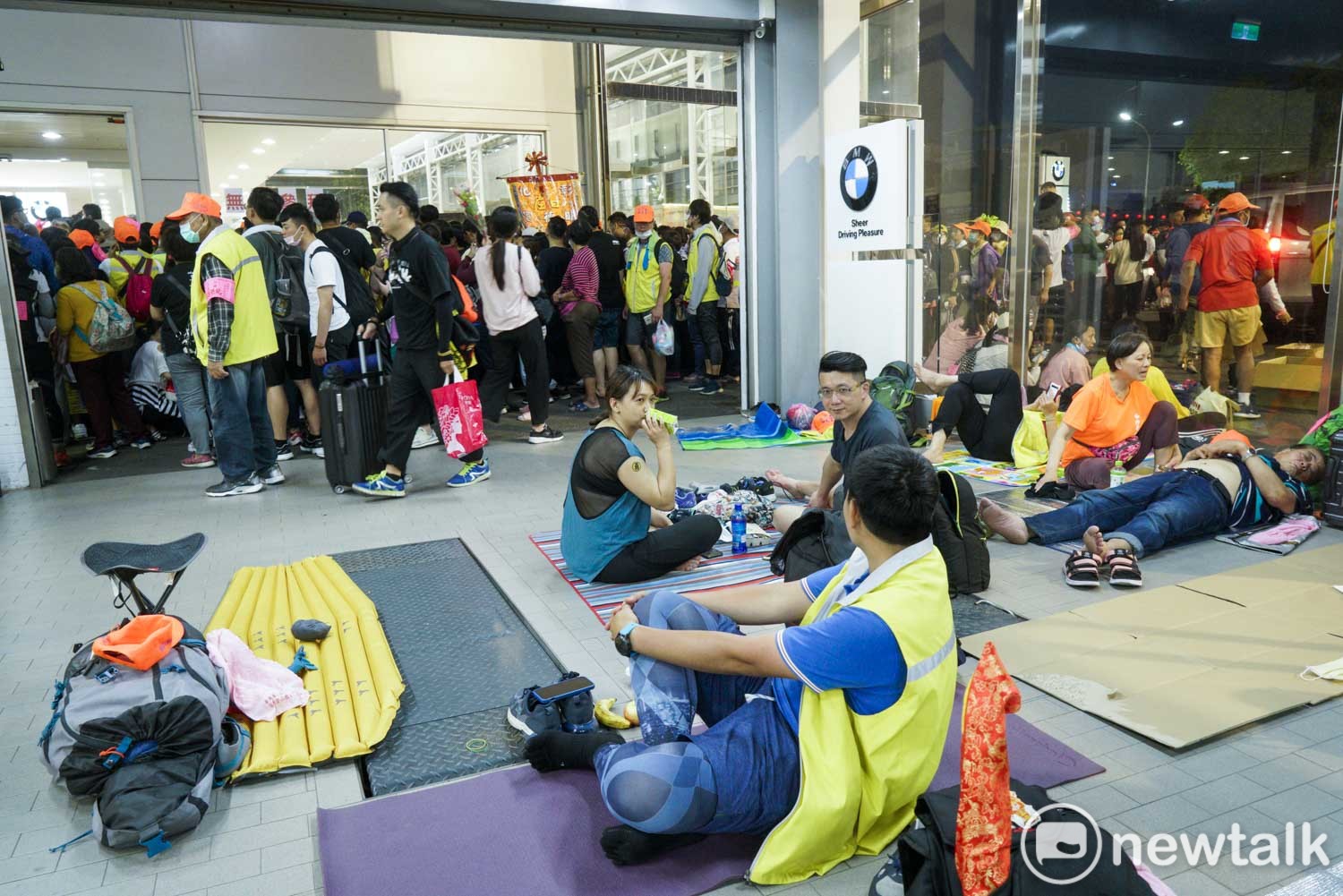 數百位進香客在BMW花壇維修中心內打地鋪休息,緊鄰維修中心的展示間,正是『粉紅超跑』白沙屯媽祖駐駕所在。 圖:張良一/攝 數百位進香客在BMW花壇維修中心內打地鋪休息,緊鄰維修中心的展示間,正是『粉紅超跑』白沙屯媽祖駐駕所在。 圖:張良一/攝