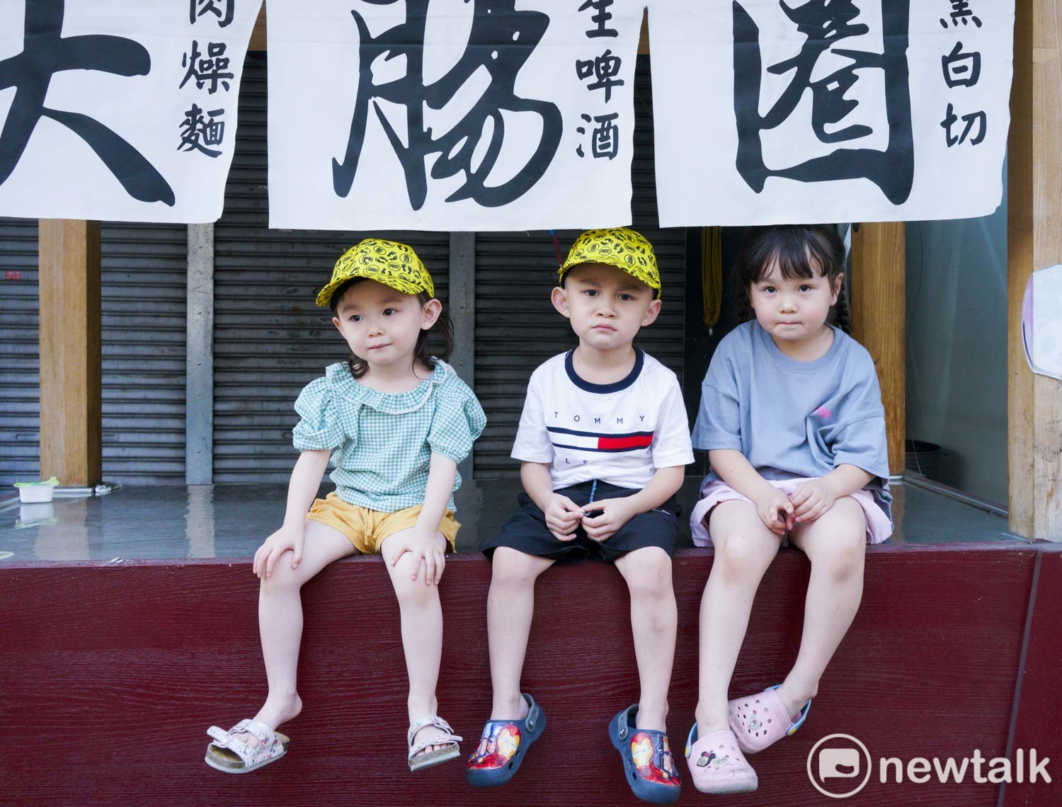 三位小朋友坐在彰化市中山路上賣大腸圈的攤子上,看著白沙屯媽祖往北港朝天宮進香的盛況。 圖:張良一/攝 三位小朋友坐在彰化市中山路上賣大腸圈的攤子上,看著白沙屯媽祖往北港朝天宮進香的盛況。 圖:張良一/攝