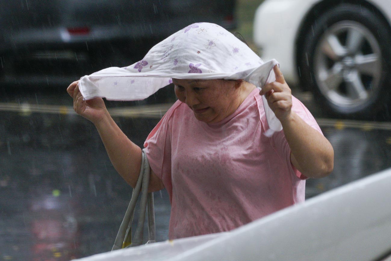 台北市區上午下了一長大雨,一位民眾用衣服遮雨。 圖:張良一/攝 台北市區上午下了一長大雨,一位民眾用衣服遮雨。 圖:張良一/攝