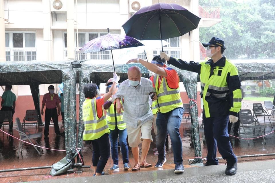 員警幫施打疫苗的長輩打傘。 圖:高雄市政府/提供 員警幫施打疫苗的長輩打傘。 圖:高雄市政府/提供