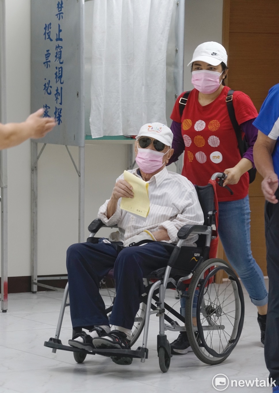 一位老黨員坐著輪椅,並在外籍移工的協助下投票。 圖:張良一/攝 一位老黨員坐著輪椅,並在外籍移工的協助下投票。 圖:張良一/攝