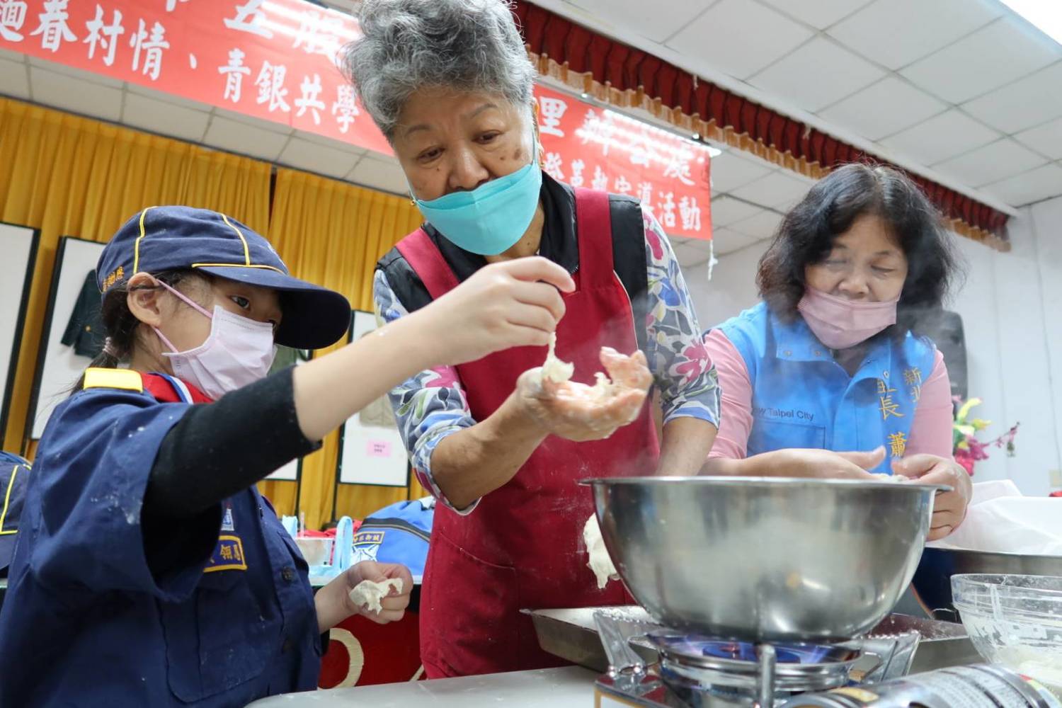 昝姜老奶奶 (中)表示,這次除了讓小朋友學習搓揉麵糰、醒麵、揉出條狀麵糰到捏。 圖:新北市民政局提供 昝姜老奶奶 (中)表示,這次除了讓小朋友學習搓揉麵糰、醒麵、揉出條狀麵糰到捏。 圖:新北市民政局提供