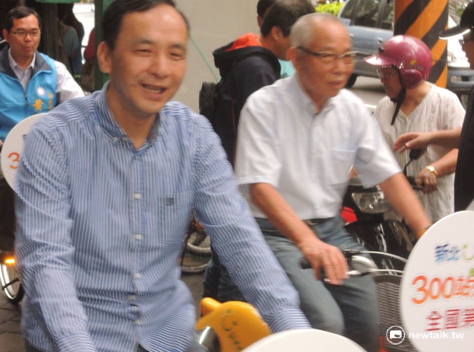 有位女性民眾的機車停放在新北市長朱立倫騎乘YouBike動線中,但機車一時發不動而遭工作人員的催趕,朱立倫一行人則神情自若的從一旁騎YouBike抵達會場。 圖:陳冠廷/攝 有位女性民眾的機車停放在新北市長朱立倫騎乘YouBike動線中,但機車一時發不動而遭工作人員的催趕,朱立倫一行人則神情自若的從一旁騎YouBike抵達會場。 圖:陳冠廷/攝