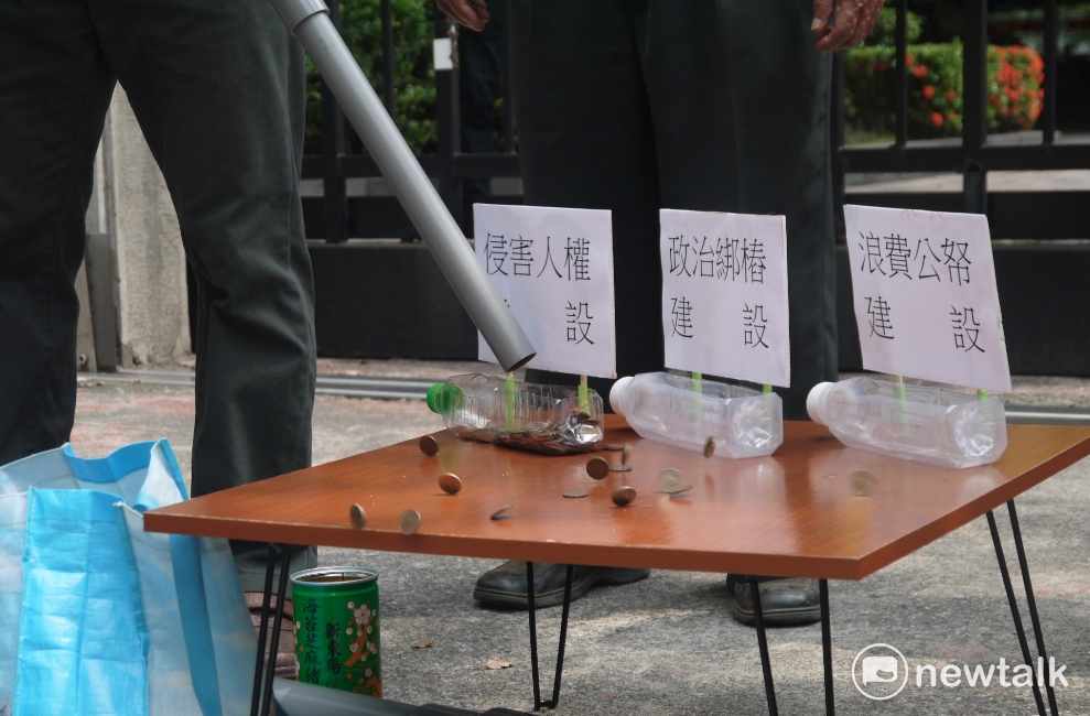 自救會居民演起行動劇,象徵拓寬道路的經費都拿去綁樁、迫遷居民與浪費公帑。 圖:鍾孟軒/攝 自救會居民演起行動劇,象徵拓寬道路的經費都拿去綁樁、迫遷居民與浪費公帑。 圖:鍾孟軒/攝