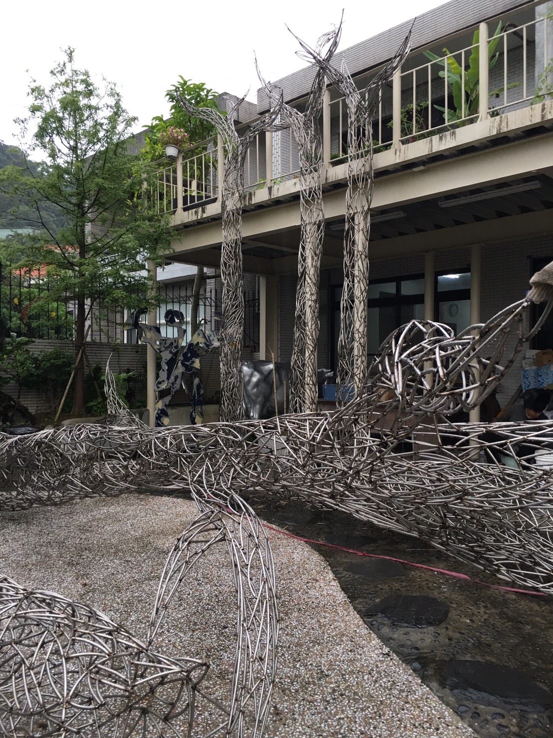 藝術家劉柏村挑戰以不鏽鋼材質製作白千層樹,與真實存在的白千層林道,相映成趣。 圖:桃園市文化局提供 藝術家劉柏村挑戰以不鏽鋼材質製作白千層樹,與真實存在的白千層林道,相映成趣。 圖:桃園市文化局提供