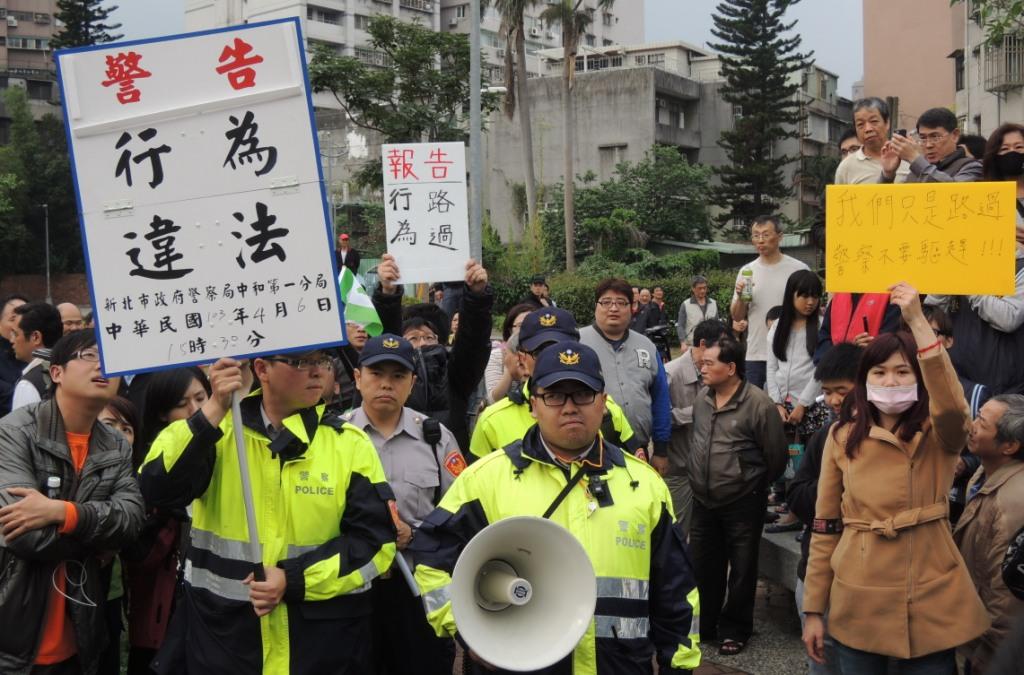警方一度舉牌警告「行為違法」,卻遭民眾以高舉「我們只是路過,警察不要驅趕」、「報告,行為路過」的標語。圖:陳冠廷/攝 警方一度舉牌警告「行為違法」,卻遭民眾以高舉「我們只是路過,警察不要驅趕」、「報告,行為路過」的標語。圖:陳冠廷/攝