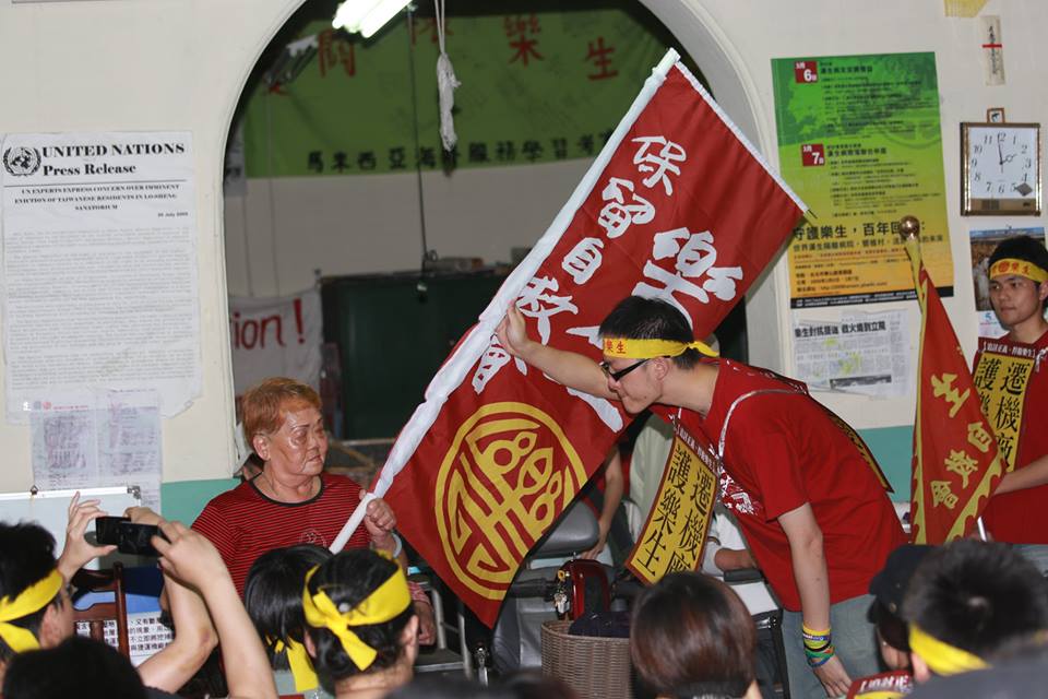 台大學生洪崇晏從樂生保留自救會的院民手上接過旗子。圖3之2:林雨佑/攝 台大學生洪崇晏從樂生保留自救會的院民手上接過旗子。圖3之2:林雨佑/攝