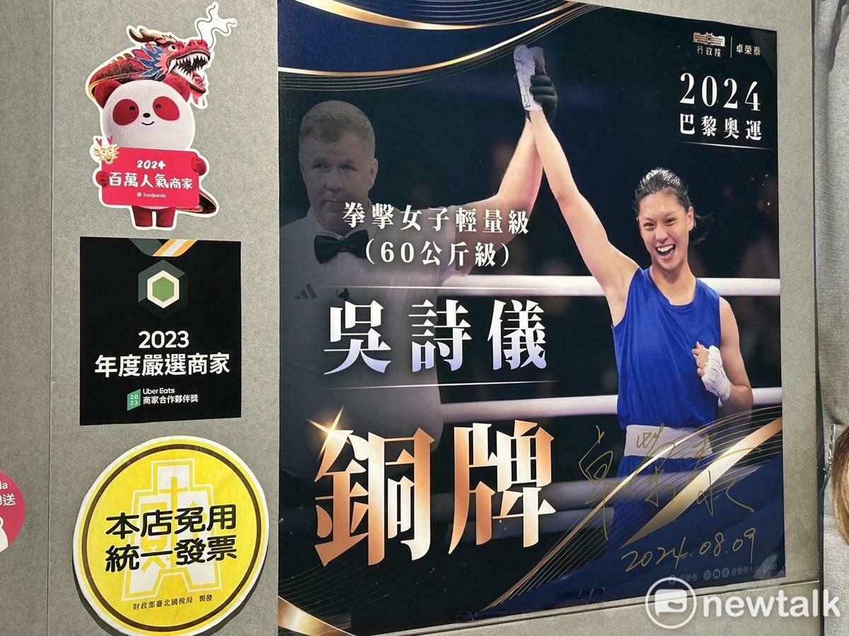  吳詩儀家中的麵店掛上行政院的恭賀圖卡海報，院長卓榮泰也在上頭簽名。 圖：黃宣尹攝 